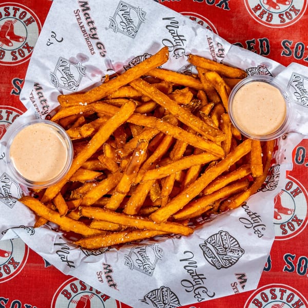 Matty G's Steakburgers' basket of golden fries with two dipping sauces on a Red Sox tablecloth.